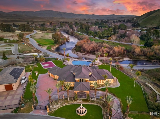 aerial view at dusk featuring a water and mountain view