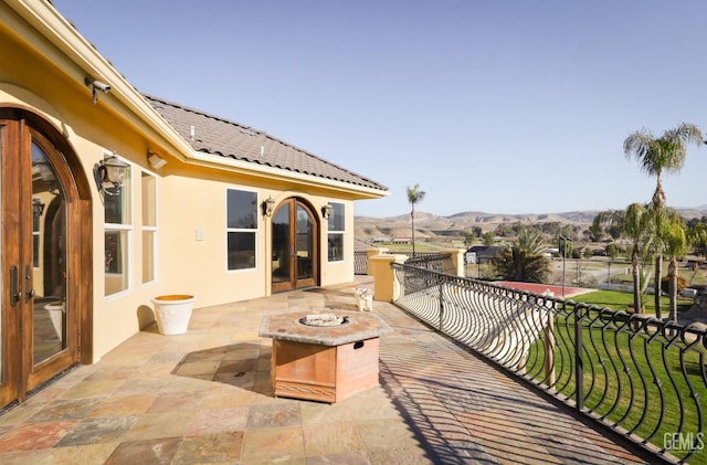 view of patio / terrace featuring a balcony, a mountain view, and a fire pit