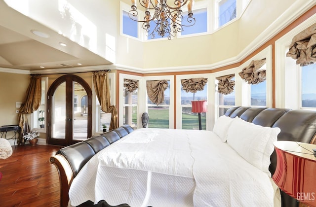 bedroom featuring a high ceiling, hardwood / wood-style floors, french doors, an inviting chandelier, and access to exterior