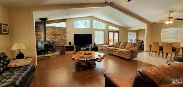 living room featuring tile patterned flooring, ceiling fan, a wood stove, and lofted ceiling