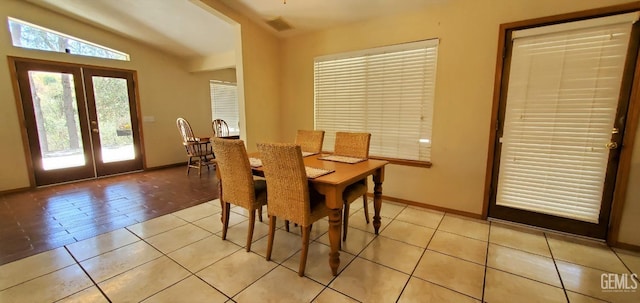 tiled dining room featuring french doors and lofted ceiling