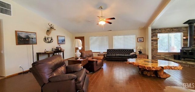 living room with ceiling fan, wood-type flooring, a wood stove, and vaulted ceiling