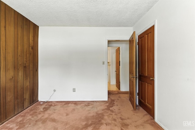 700 Mulberry St, Tehachapi, CA 93561 - unfurnished bedroom with light carpet, a textured ceiling, wood walls, and a closet