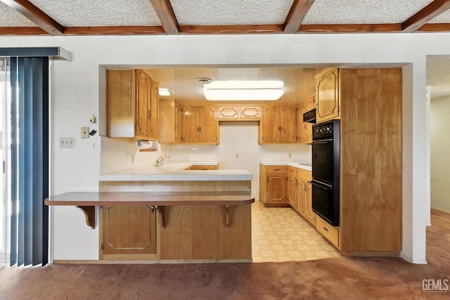 700 Mulberry St, Tehachapi, CA 93561 - kitchen featuring a peninsula, beam ceiling, light countertops, light colored carpet, and light floors
