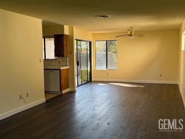 unfurnished living room featuring dark wood-type flooring, a ceiling fan, baseboards, and a textured ceiling