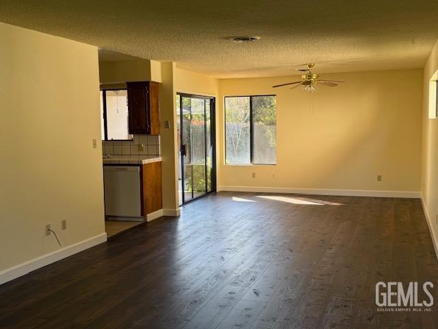 unfurnished living room with baseboards, a textured ceiling, dark wood-style floors, and a ceiling fan