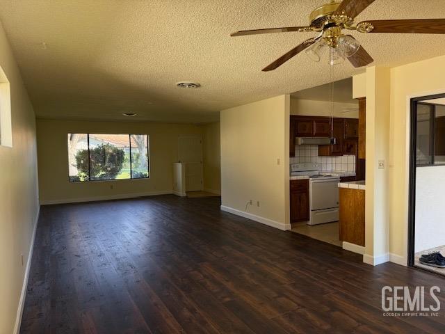 unfurnished living room with dark wood-style floors, baseboards, visible vents, ceiling fan, and a textured ceiling