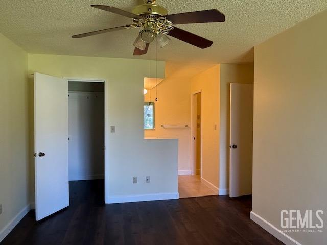 unfurnished bedroom with ceiling fan, baseboards, a textured ceiling, and wood finished floors