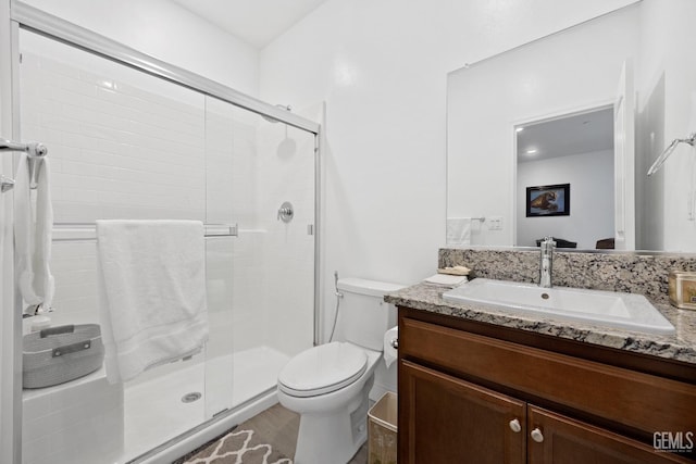 full bath with a shower stall, vanity, and toilet