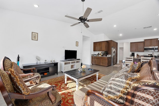 living area with lofted ceiling, light wood-style floors, visible vents, and a ceiling fan