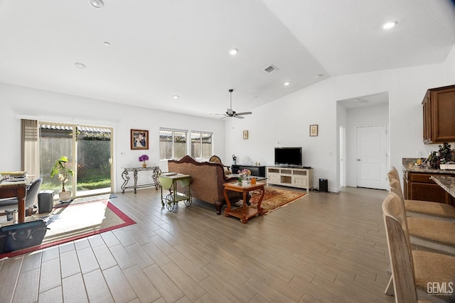 living area featuring lofted ceiling, wood finished floors, visible vents, and a ceiling fan