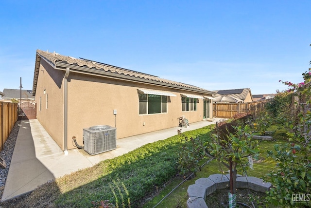 rear view of house with a tile roof, a fenced backyard, a lawn, and stucco siding