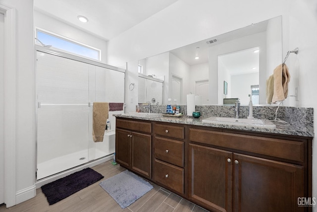 bathroom with wood finished floors, a stall shower, a sink, and visible vents