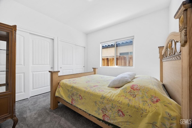 bedroom featuring dark colored carpet and two closets