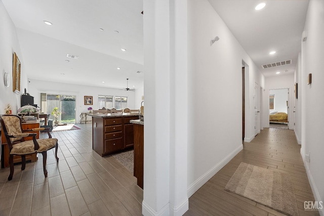 hall with light wood-type flooring, visible vents, and recessed lighting