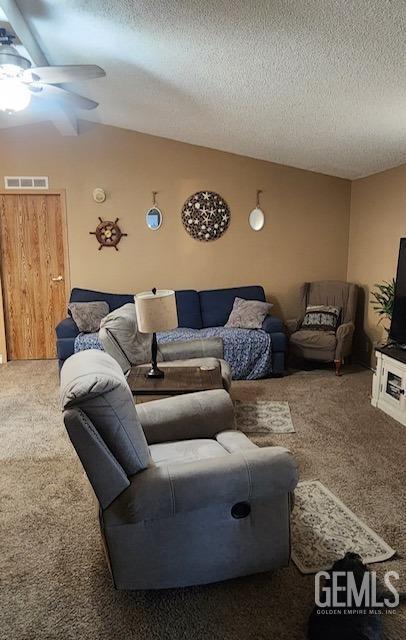 carpeted living room featuring a textured ceiling and ceiling fan