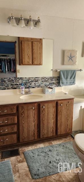 bathroom featuring decorative backsplash, vanity, and toilet