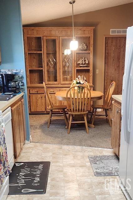 carpeted dining area featuring a textured ceiling, lofted ceiling, and sink