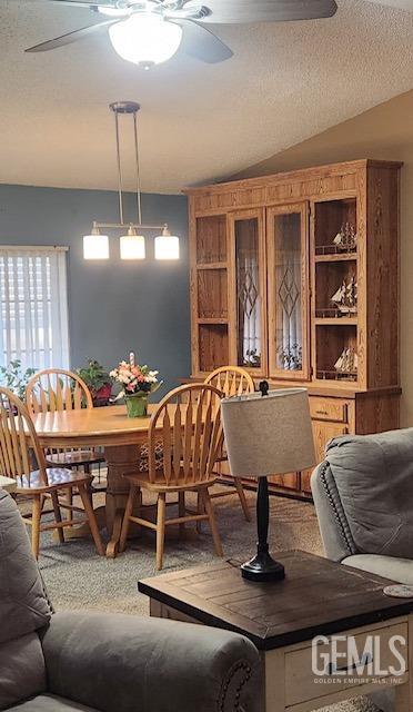 dining room with carpet, a textured ceiling, and vaulted ceiling