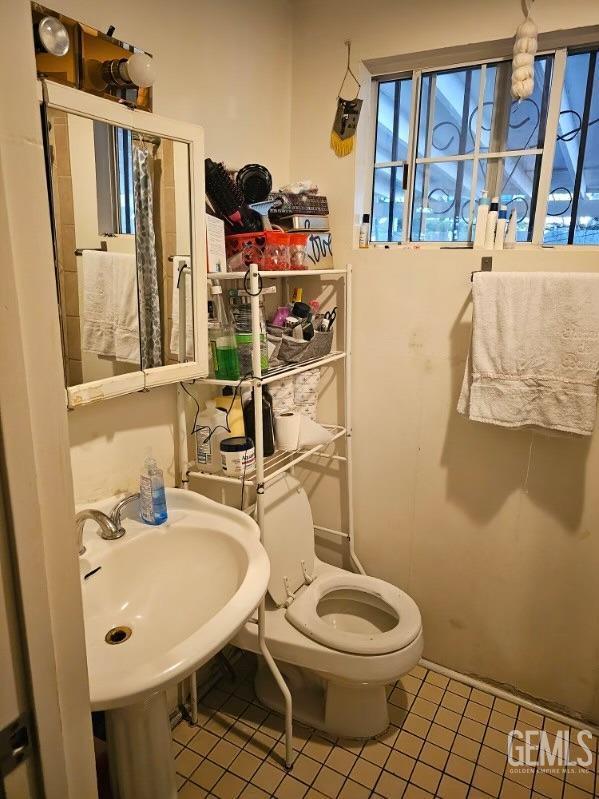 bathroom with toilet, tile patterned floors, and sink