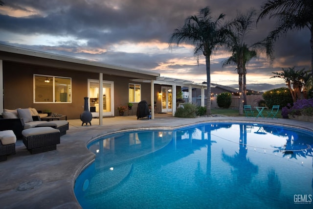 9900 Swansboro Way, Bakersfield, CA 93314 - pool at dusk featuring french doors, a patio, and an outdoor living space