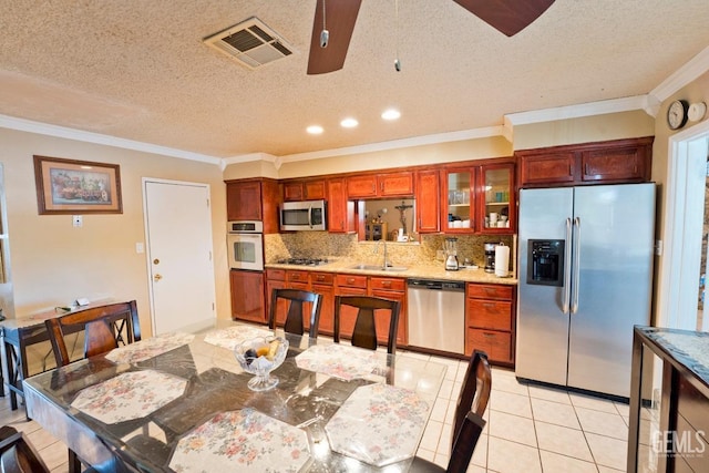 kitchen featuring tasteful backsplash, visible vents, stainless steel appliances, light countertops, and a sink