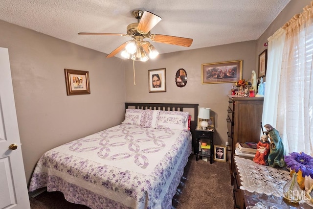 bedroom featuring a ceiling fan, dark colored carpet, and a textured ceiling