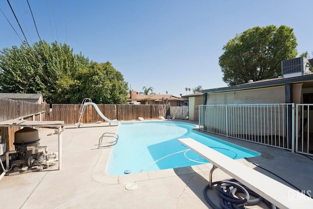 view of swimming pool featuring a patio, a water slide, a fenced backyard, a diving board, and a fenced in pool