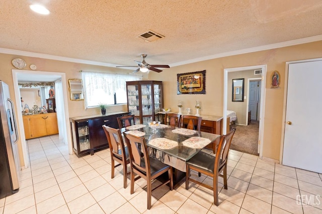 dining room with light tile patterned floors, visible vents, a ceiling fan, a textured ceiling, and crown molding