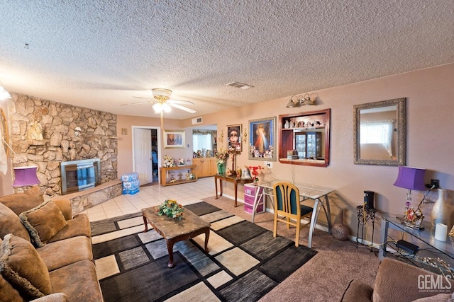 living area with a textured ceiling, a stone fireplace, plenty of natural light, and visible vents