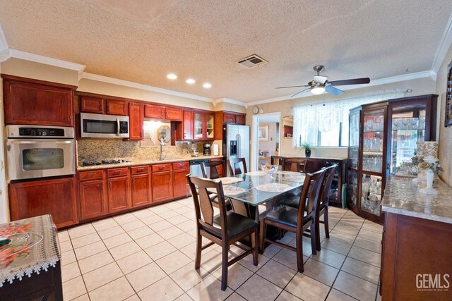 dining room with light tile patterned floors, ceiling fan, a textured ceiling, visible vents, and ornamental molding