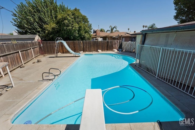 view of pool with a water slide, a fenced backyard, a diving board, a fenced in pool, and a patio area