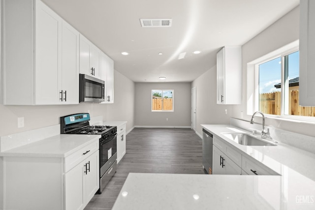 707 Poinsettia St, Bakersfield, CA 93307 - kitchen with stainless steel appliances, a sink, baseboards, light wood-type flooring, and white cabinets