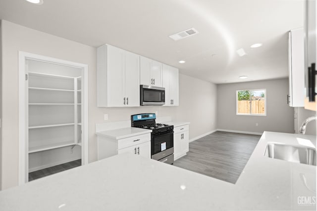 707 Poinsettia St, Bakersfield, CA 93307 - kitchen featuring gas range oven, stainless steel microwave, a sink, wood finished floors, and recessed lighting