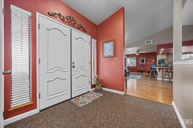 foyer featuring visible vents, vaulted ceiling, and baseboards