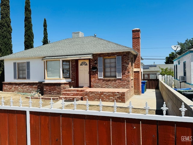 104 E Kern St, Taft, CA 93268 - view of front of house featuring brick siding, a shingled roof, a fenced front yard, and a chimney