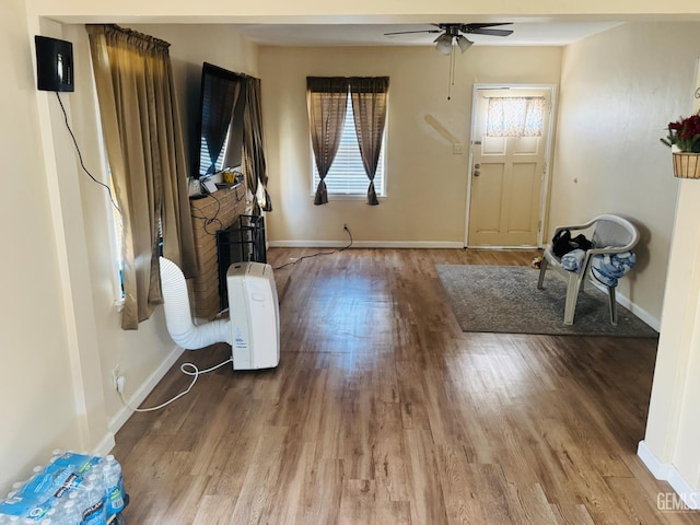 104 E Kern St, Taft, CA 93268 - unfurnished living room featuring wood finished floors, a ceiling fan, baseboards, and a fireplace