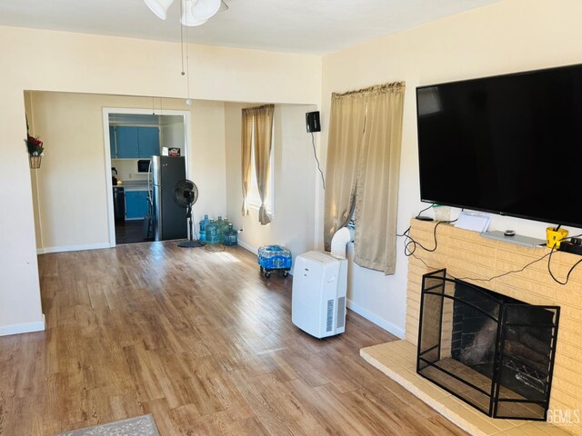 104 E Kern St, Taft, CA 93268 - unfurnished living room featuring wood finished floors, ceiling fan, baseboards, and a fireplace