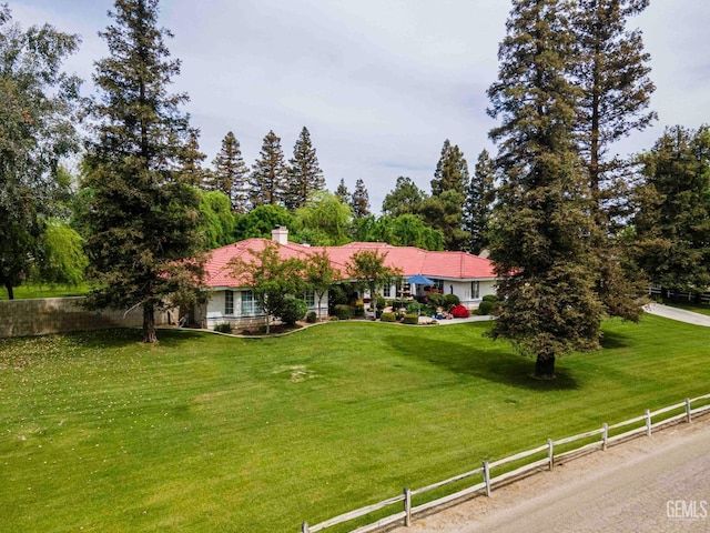 ranch-style home featuring a front yard, a chimney, and fence