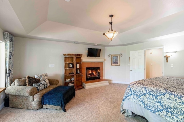 bedroom with a fireplace, baseboards, a tray ceiling, and carpet floors