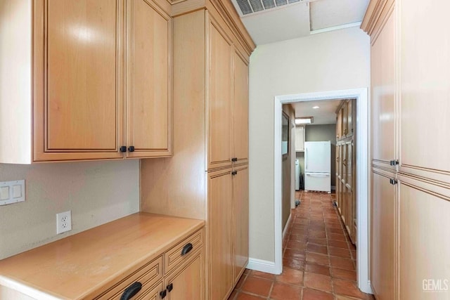 interior space with visible vents, light countertops, freestanding refrigerator, light brown cabinetry, and tile patterned flooring