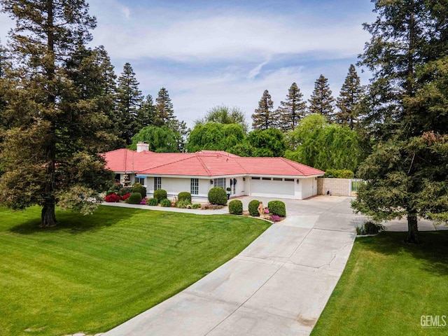view of front facade featuring a tile roof, a front yard, a garage, concrete driveway, and fence