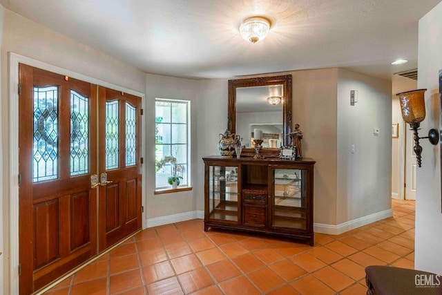 foyer entrance with light tile patterned flooring and baseboards