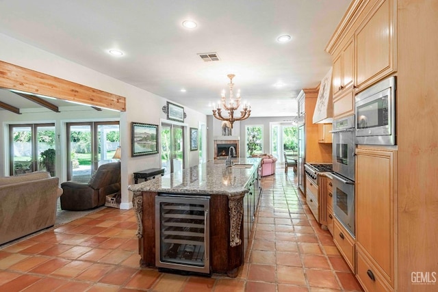 kitchen featuring a sink, stainless steel appliances, wine cooler, visible vents, and open floor plan