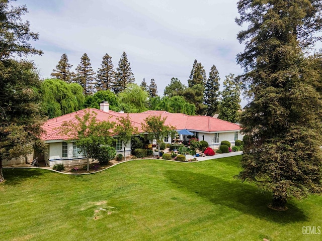 view of front of property featuring a chimney, stucco siding, and a front yard