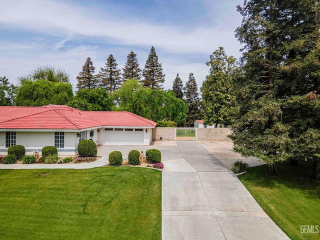 view of front of property with concrete driveway, a tile roof, a front yard, an attached garage, and fence