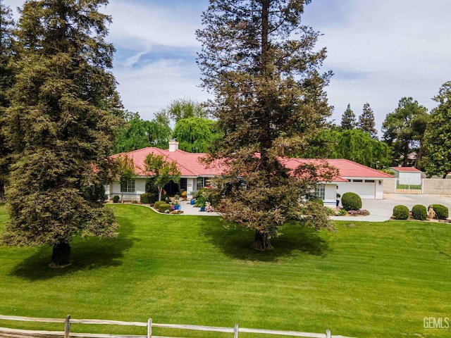 view of front of home with a tile roof, a front lawn, driveway, and fence