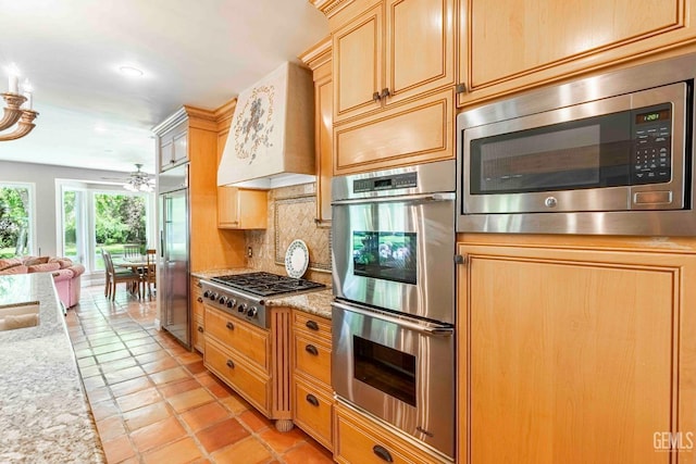 kitchen featuring tasteful backsplash, custom range hood, built in appliances, ceiling fan, and open floor plan