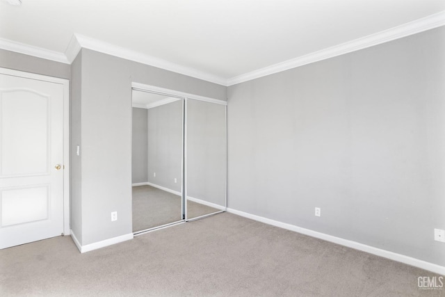 unfurnished bedroom featuring crown molding, light colored carpet, and a closet