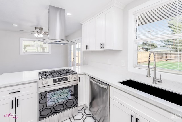 kitchen featuring white cabinetry, island exhaust hood, stainless steel appliances, sink, and ceiling fan